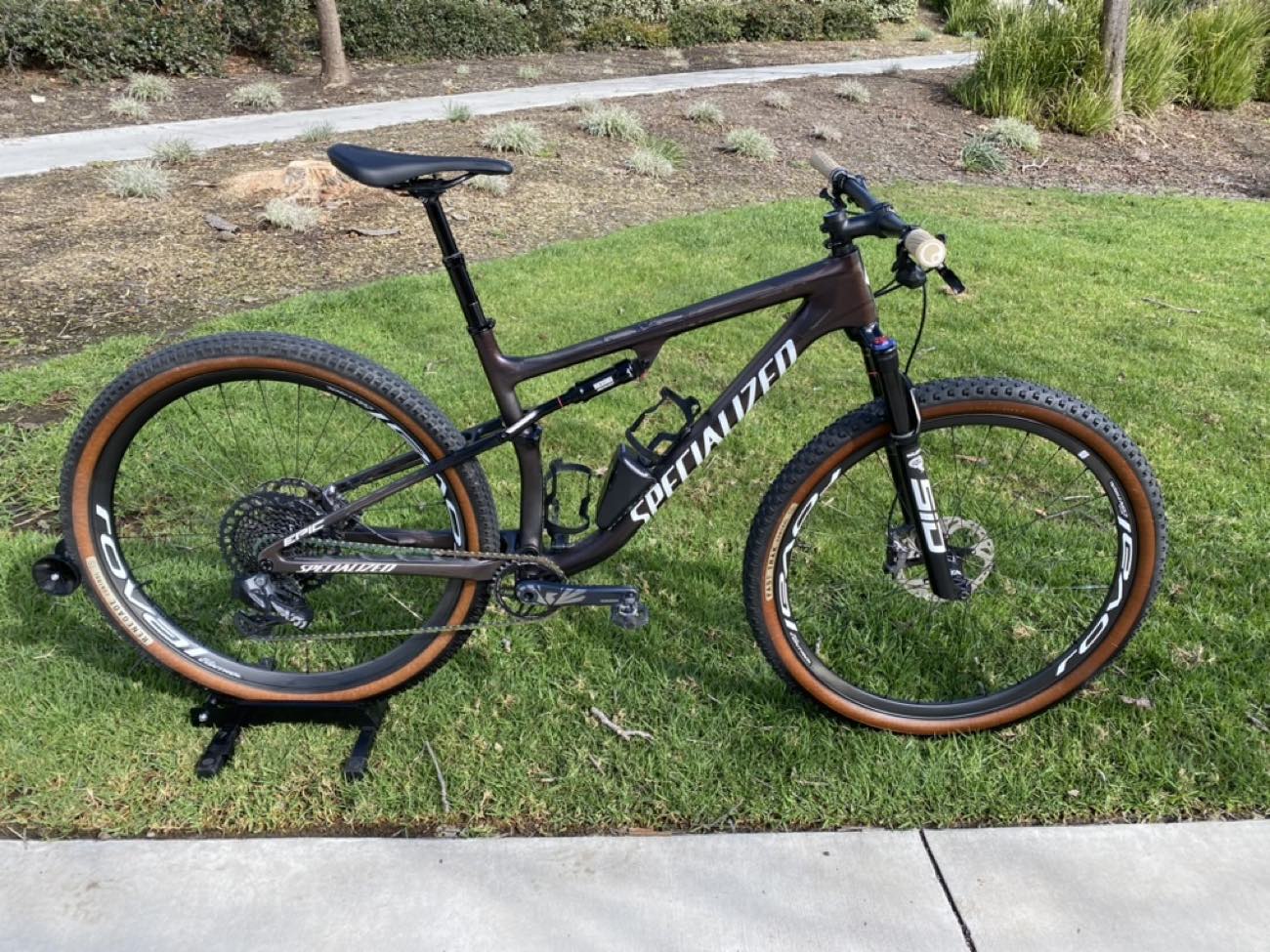 Side profile of a carbon cross-country full-suspension bike on grass